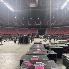 the inside of an empty arena with several large boxes on the floor and people walking around