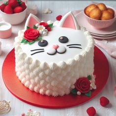 a cake with white frosting and red flowers on top, sitting on a table