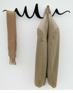 two pieces of cloth hanging from hooks on a white wall with black cords attached to them