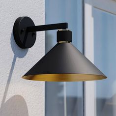 a black and gold wall light on the side of a building with windows in the background