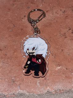 a keychain with an anime character on it sitting on a stone surface next to a brick wall