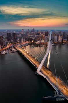 an aerial view of a bridge in the city at night with lights shining on it