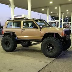 an suv parked in front of a gas station with large tires on it's rims