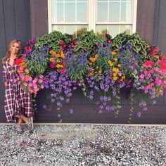 a woman standing next to a window filled with flowers