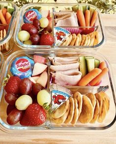 three plastic containers filled with food on top of a wooden table next to fruit and veggies