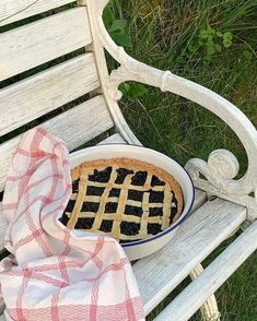 a pie sitting on top of a white bench next to a red and white checkered towel