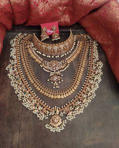 an elaborate necklace and earring set is displayed on the floor in front of a red cloth