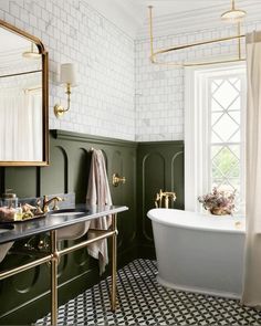 a bathroom with green walls, black and white tile flooring and gold fixtures on the bathtub