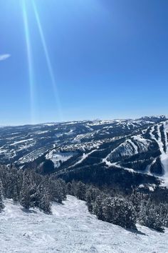 the sun shines brightly over a snowy mountain landscape with trees and snow - capped mountains