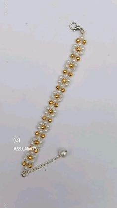 a white and gold beaded bracelet on a silver chain with a metal hook in the middle