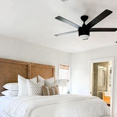 a bedroom with white bedding and black ceiling fan