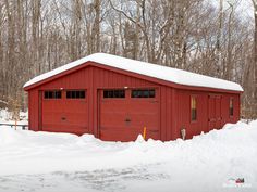 a red garage with snow on the ground and trees in the background