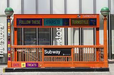 an orange bus stop sitting on the side of a road next to a tall building