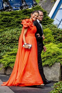 a man and woman in formal wear walking down the street with their arms around each other