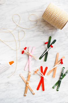 popsicle stick crafts with yarn and scissors on a marble countertop next to a roll of twine