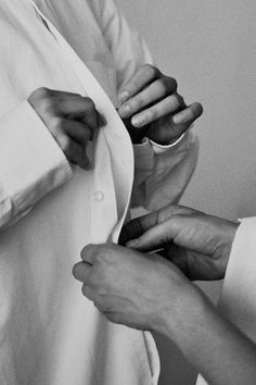 black and white photograph of two hands pulling up a shirt with the sleeves folded open