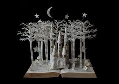 an open book with paper cut out of it and trees on the pages, in front of