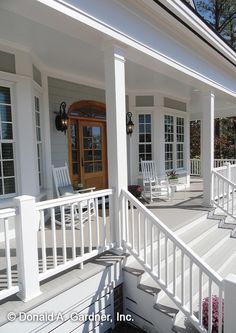 the front porch of a house with white railings and chairs on either side of it