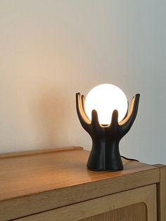 a black lamp sitting on top of a wooden dresser