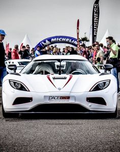 a white sports car parked in front of a crowd