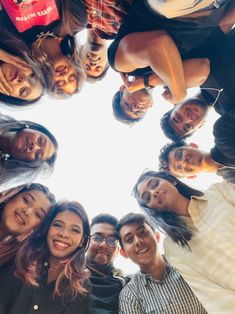 a group of people standing in a circle looking up at the camera with their heads together