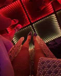 the legs and feet of a woman in red tights are lit up by colorful lights