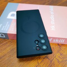 a black cell phone sitting on top of a wooden table next to a book case