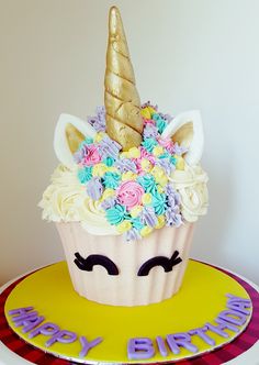 a cupcake decorated with flowers and unicorn's horn is on top of a plate