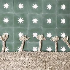 four palm trees on a rug against a green wall with white stars in the background