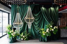 a room with green curtains and chandeliers hanging from the ceiling