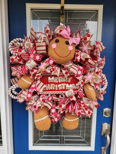 a door hanger that has a teddy bear on it and is decorated with red, white and pink ribbons