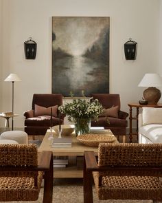 a living room with wicker furniture and a painting on the wall above it's coffee table