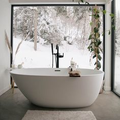 a large white bathtub sitting in front of a window next to a rug on the floor