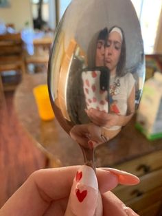 a hand holding a wine glass with a reflection of two people in it and a heart painted on the side