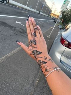 a woman's hand with tattoos on it is next to a parked car in the street