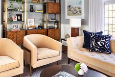 a living room with couches, chairs and bookshelves on the wall in front of windows