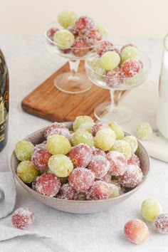 a bowl filled with sugar covered candies next to two wine glasses and a bottle