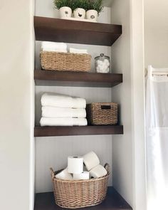 the shelves in this bathroom are filled with towels and toilet paper, which also have wicker baskets on them