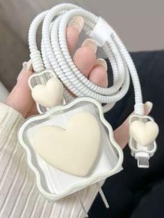 a person holding a white heart shaped object in their hand and some cords attached to it