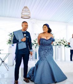 a man and woman standing next to each other in front of a white tent with flowers