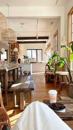 a wooden table sitting inside of a kitchen next to a plant on top of a hard wood floor