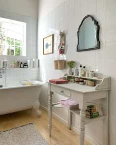 a white bath tub sitting next to a wooden floor in a bathroom under a mirror