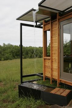 a small wooden building with windows in the grass