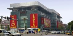 cars are parked in front of a large building with chinese writing on the side of it