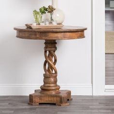 a wooden table with a vase on top of it next to a white wall and door