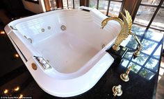 a large white bath tub sitting on top of a black counter next to a window