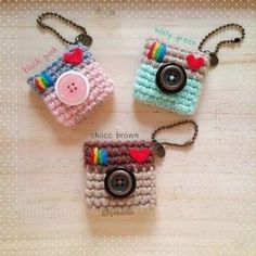 three small crocheted purses with buttons and hearts on them sitting on a table