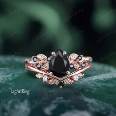 a black diamond ring on top of a leafy green surface with white and black stones