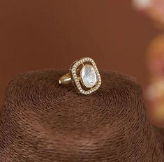 a close up view of a ring on top of a brown hat with flowers in the background