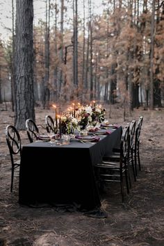 an outdoor table set up with black linens, candles and floral centerpieces